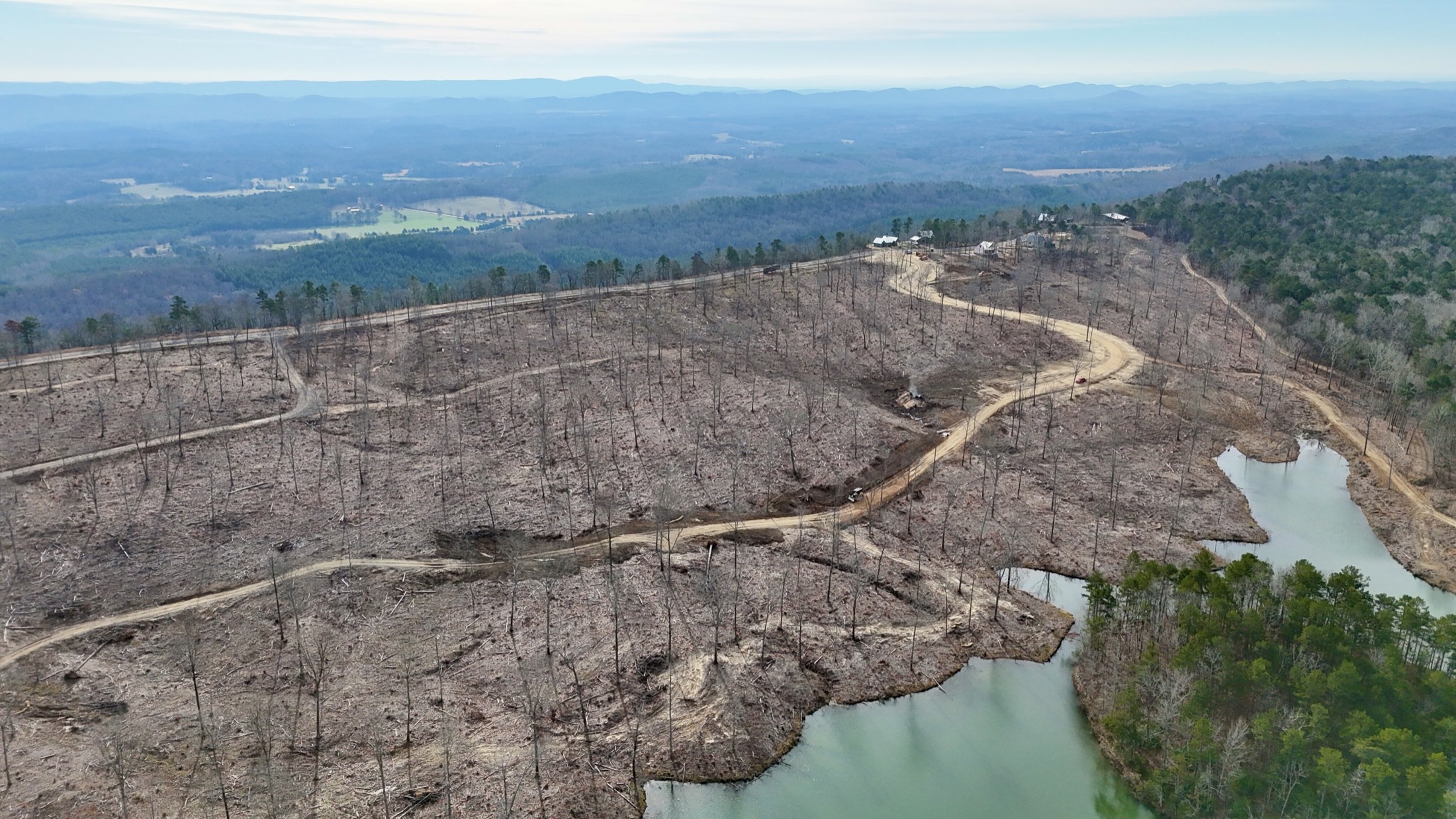 Aerial view of roads, open ground, lake edge, and mountain ridges at Cairnwood