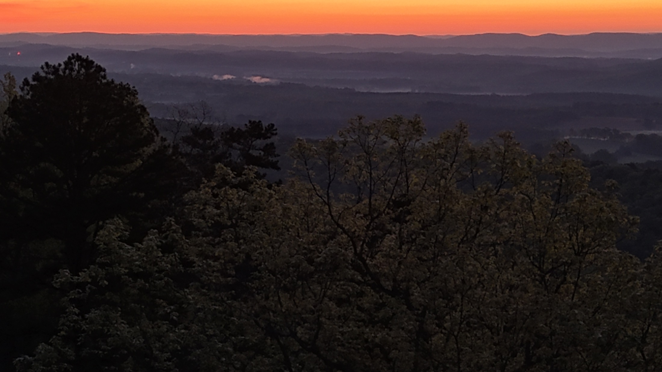 Sunrise over woodland and layered ridges seen from Cairnwood